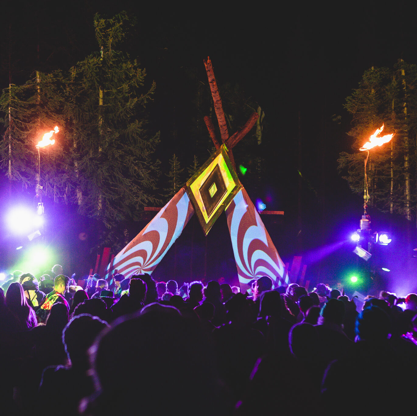 Ourdoor stage made of fabric and wood illuminated by colorful projection mapping